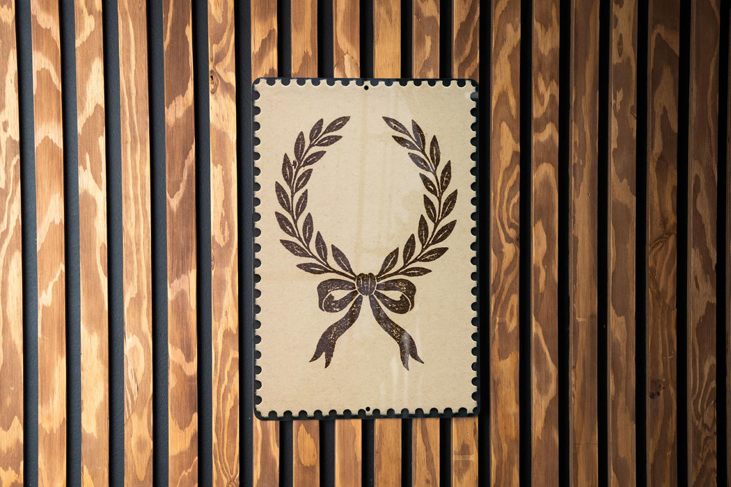 a decorative wreath with a ribbon design, displayed on a wooden wall.