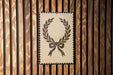 a decorative wreath with a ribbon design, displayed on a wooden wall.