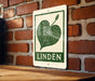A sign with a leaf graphic and the word "LINDEN" printed on it is displayed on a brick wall.