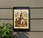 a church depicted on a postage stamp-like frame, mounted on a wall next to a plant.
