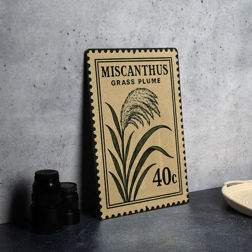 a framed stamp with a plant illustration and text, placed on a table next to some black camera lenses.