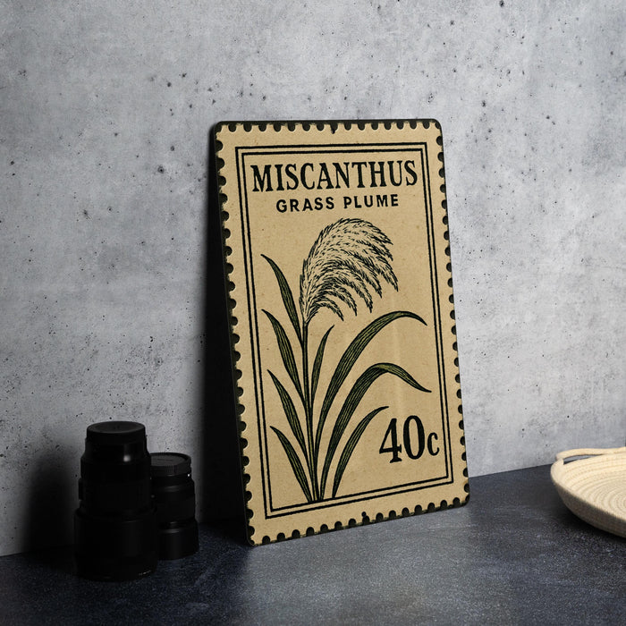 a framed stamp with a plant illustration and text, placed on a table next to some black camera lenses.
