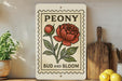 A vintage-style sign with a peony flower and the text "PEONY BUD AND BLOOM" is displayed on a shelf, accompanied by a wooden cutting board and a potted plant.