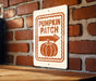 A sign on a brick wall that reads "PUMPKIN PATCH" with an arrow pointing to the right.