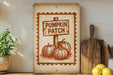 a rustic wooden sign with a pumpkin patch illustration, placed on a shelf next to a wooden cutting board and some lemons.