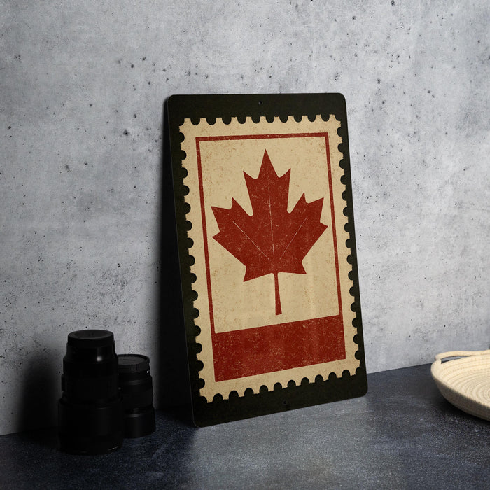 a framed Canadian maple leaf on a dark surface, with a stack of black camera lenses and a white dish visible in the background.