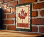 a brick wall with a vintage-style metal sign displaying a red maple leaf on it.