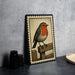 A framed illustration of a red-headed bird perched on a wooden fence is displayed on a gray countertop.