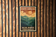 A vintage-style metal sign with the text "SOUTH CAROLINA" and "BLUE RIDGE FOOTHILLS" is displayed on a wooden wall.
