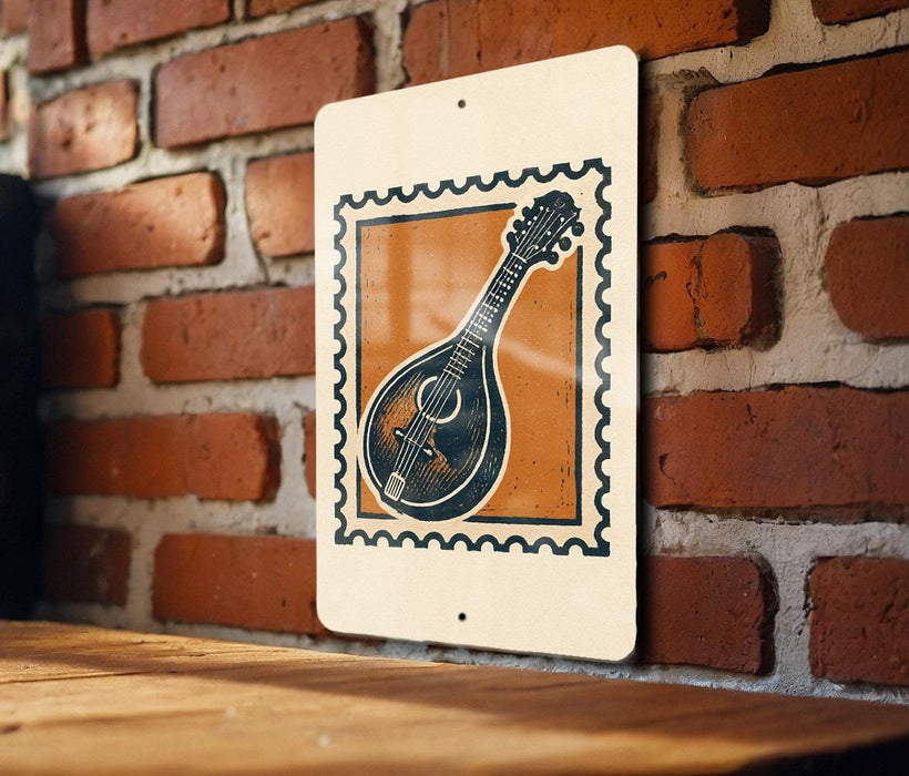 A white sign with a black and orange design featuring a musical instrument, such as a guitar or banjo, is hanging on a brick wall.