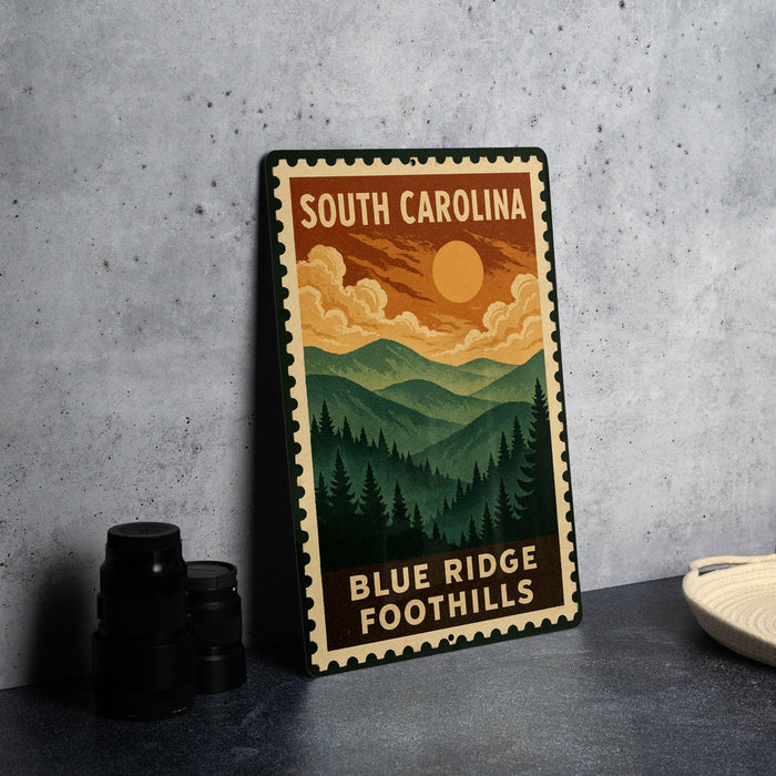 A metal sign with a mountain landscape and a sun in the sky, featuring the text "SOUTH CAROLINA" and "BLUE RIDGE FOOTHILLS".
