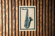 A framed image of a saxophone is displayed on a wooden wall.