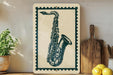 a framed illustration of a saxophone on a shelf, with a potted plant to the left and a wooden cutting board to the right.