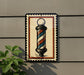 A barber pole sign is mounted on a wall, with a plant visible to the left.