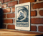 A sign with a surfboard graphic and the word "BODYBOARD" is displayed on a brick wall.