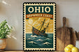 a vintage-style sign for the Ohio Shipwreck Coast, with a ship illustration and a sunset in the background.