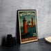 A metal stamp depicting a lighthouse scene with the text "WISCONSIN" and "LAKESHORE Lighthouses" printed on it, along with the number "25".