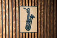 A metal sign featuring a saxophone is mounted on a wooden wall.