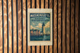 A metal sign with a vintage-style illustration of a lighthouse and a town, mounted on a wooden wall.