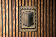 a wooden wall with a framed illustration of a rectangular object, which appears to be a musical instrument or a box.