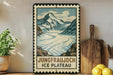 A framed illustration of a mountain landscape with a river, accompanied by the text "Jungfraujoch ICE PLATEAU" on a wooden shelf.