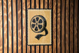 A poster with a film reel on it is displayed on a wooden wall.