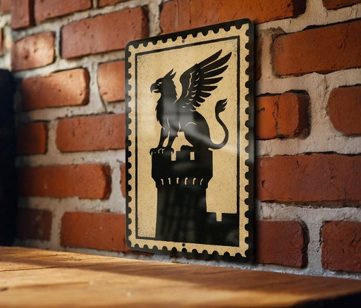 A black and white illustration of a winged lion or mythical creature is displayed on a brick wall, mounted on a wooden surface.