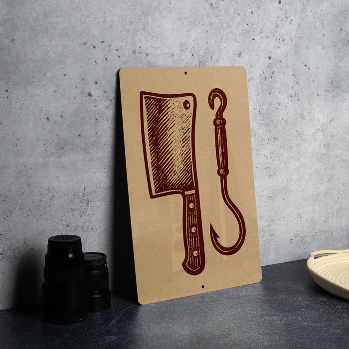 a wooden sign with a butcher knife and a hook on it, placed on a countertop next to some black containers.