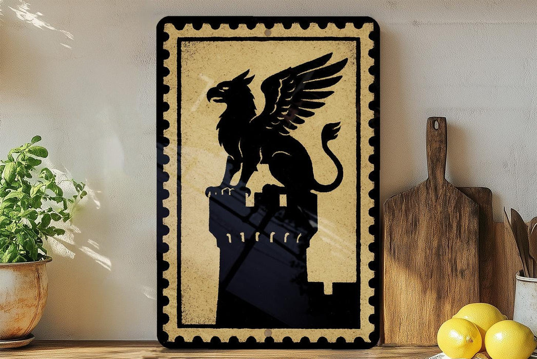 a framed artwork depicting a winged creature, possibly a mythical or fantastical being, perched atop a tower or structure. The artwork is displayed on a shelf, with a potted plant to the left and a wooden cutting board to the right.