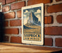 A vintage-style metal sign with a mountain landscape and the text "SHIPROCK NEW MEXICO" is displayed on a brick wall.
