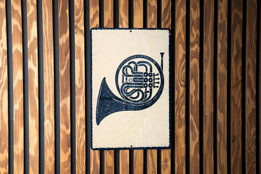 A metal sign with a black and white illustration of a horn is mounted on a wooden wall.