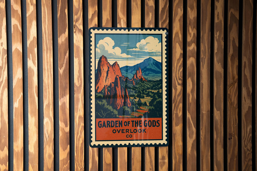 A vintage-style poster of a mountainous landscape with the text "GARDEN OF THE GODS OVERLOOK CO" displayed on a wooden wall.