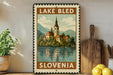 A framed vintage-style poster of Lake Bled, Slovenia, featuring a church and a lake surrounded by mountains.