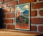 A vintage-style metal sign with a mountain landscape and clouds, mounted on a brick wall.