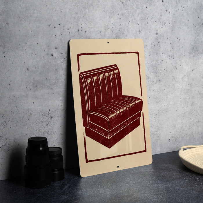 a sign with a red and white design depicting a red leather booth or booth-style chair.