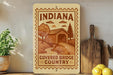 a wooden sign with the text "INDIANA COVERED BRIDGE COUNTRY" and an illustration of a covered bridge in a rural setting.