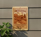 A sign for Indiana's Covered Bridge Country is displayed on a wall, featuring an illustration of a covered bridge surrounded by trees and a road.