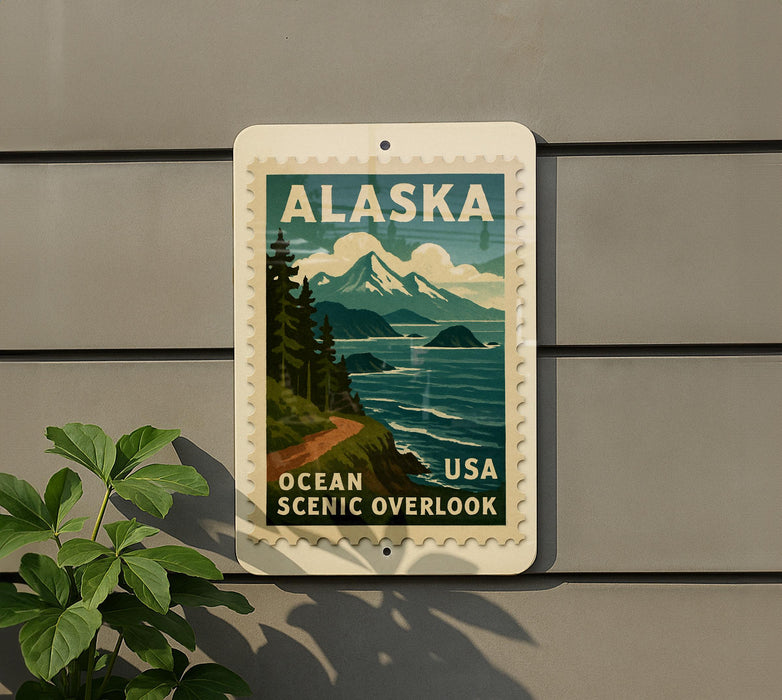 A vintage-style Alaska postage stamp is displayed on a wall, featuring a scenic mountain landscape with a winding road and ocean in the background.