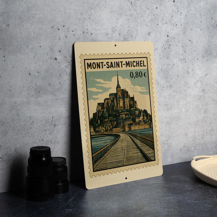 A metal sign with a vintage-style illustration of Mont-Saint-Michel, a famous island in Normandy, France.