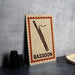 A metal sign with a picture of a bassoon on it, placed on a table next to some black camera lenses.