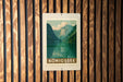 A framed poster of a mountain landscape with a lake is displayed on a wooden wall.
