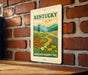 A sign for the Kentucky Wildflower Meadows Trail is displayed on a brick wall.