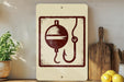 a sign with a fishing symbol, a hook, and a bobber, placed on a shelf next to a wooden cutting board and some lemons.