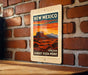A vintage-style poster of the Sunset Vista Point in New Mexico, featuring a desert landscape with mountains in the background and a warm sunset sky.