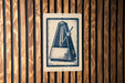 a close-up view of a sign with a stylized illustration of a metronome, which is a musical instrument used to measure time.