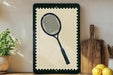 a framed tennis racket on a shelf, surrounded by kitchen utensils and a potted plant.