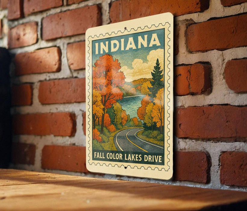 A vintage-style sign depicting a scenic autumn landscape with a road leading through it, mounted on a brick wall.