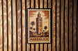 A framed image of a tower with palm trees, mounted on a wooden wall.
