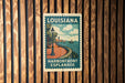 A vintage-style sign for the Louisiana Harborfront Esplanade, featuring a scenic illustration of a waterfront promenade with a lamppost and boats.