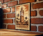 A metal sign with a picture of a tower and palm trees, mounted on a brick wall.